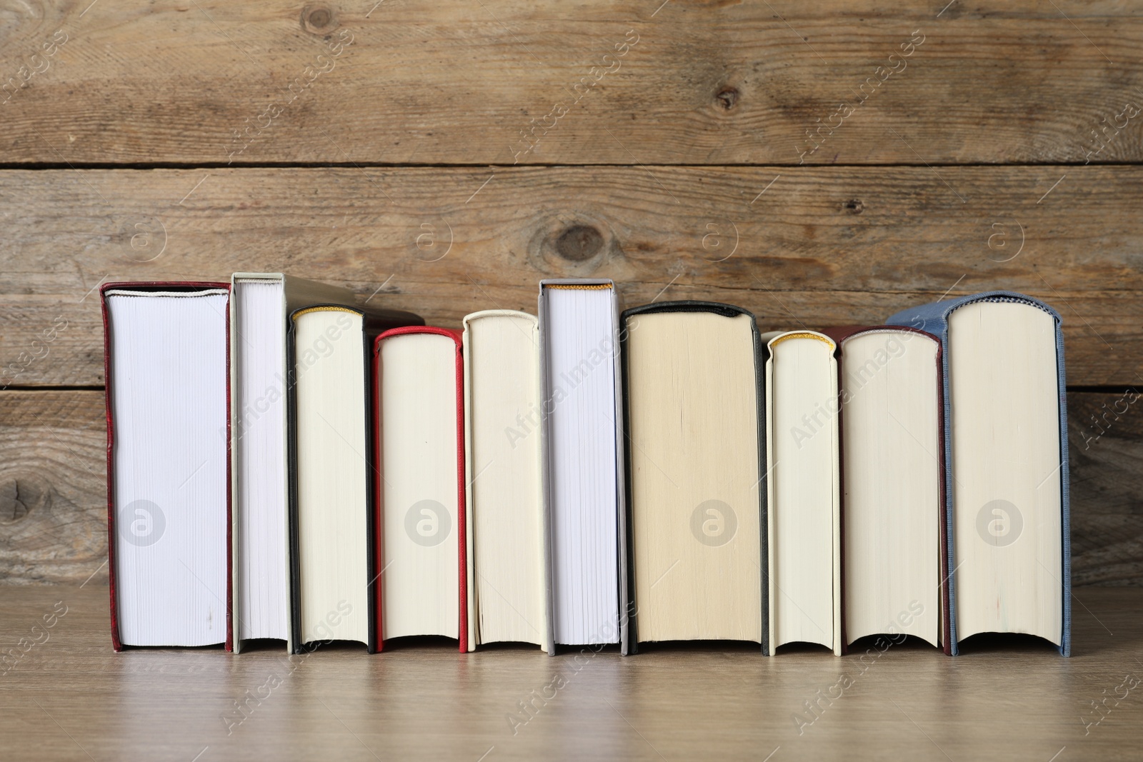 Photo of Many hardcover books on wooden table, space for text