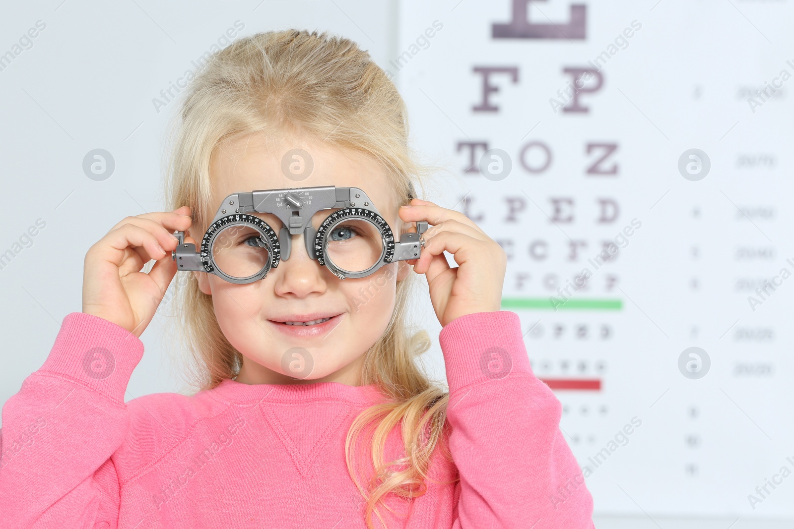 Photo of Little girl with trial frame near eye chart in hospital, space for text. Visiting children's doctor