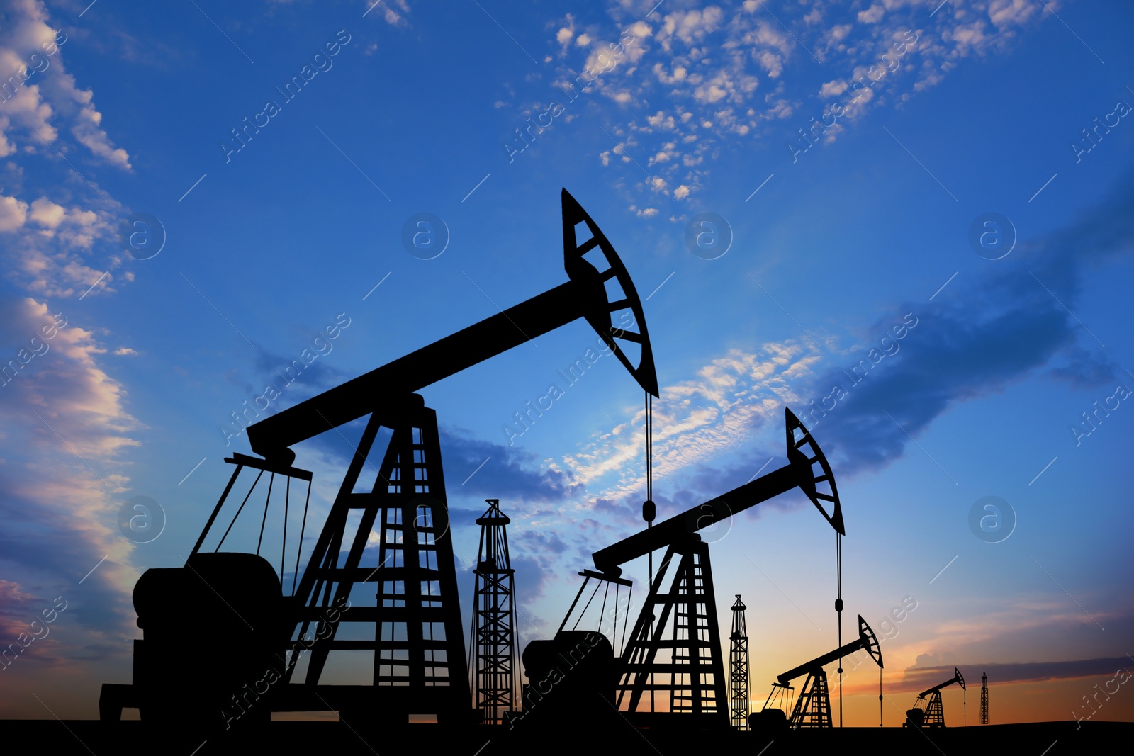 Image of Silhouettes of crude oil pumps at sunset