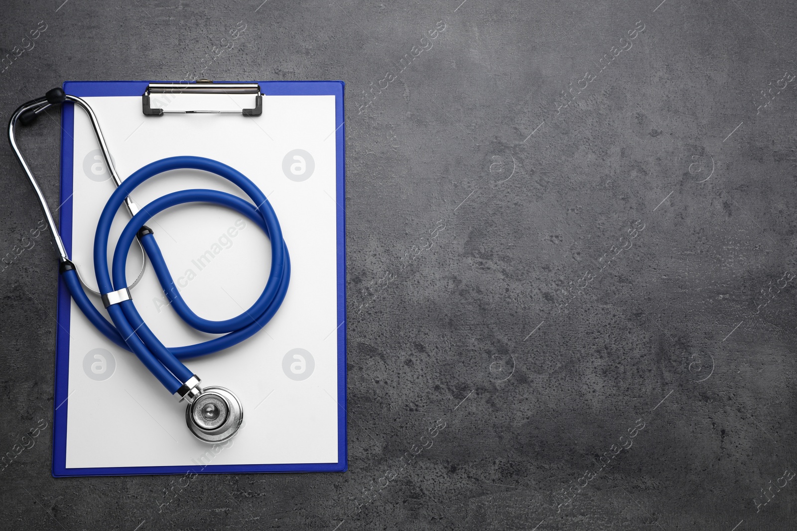 Photo of Clipboard with stethoscope on grey table, top view. Space for text