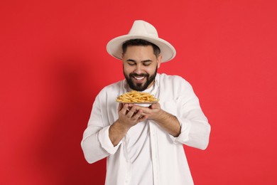 Photo of Young man with French fries on red background