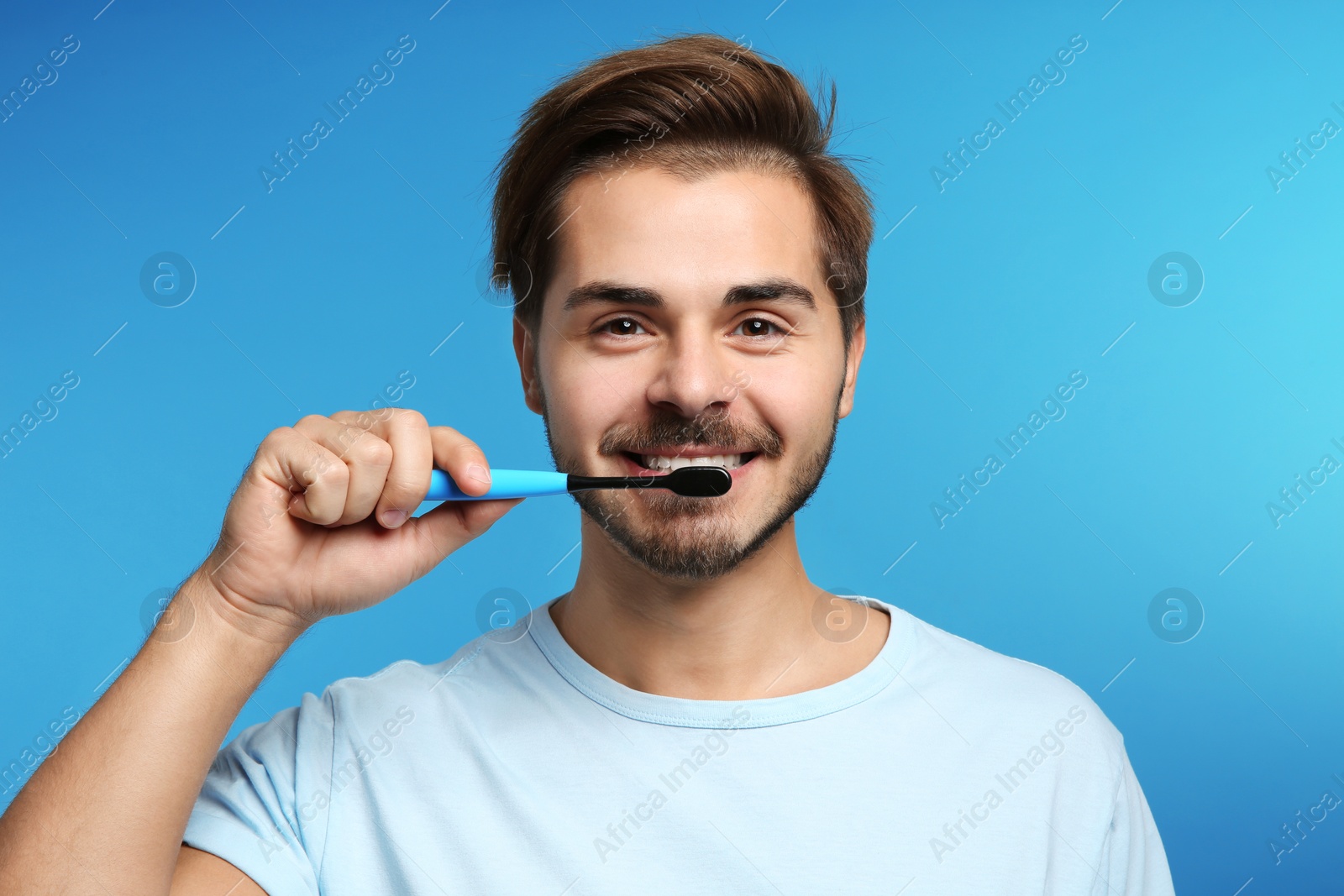 Photo of Portrait of young man with toothbrush on color background