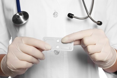 Photo of Doctor holding blister of emergency contraception pills on white background, closeup