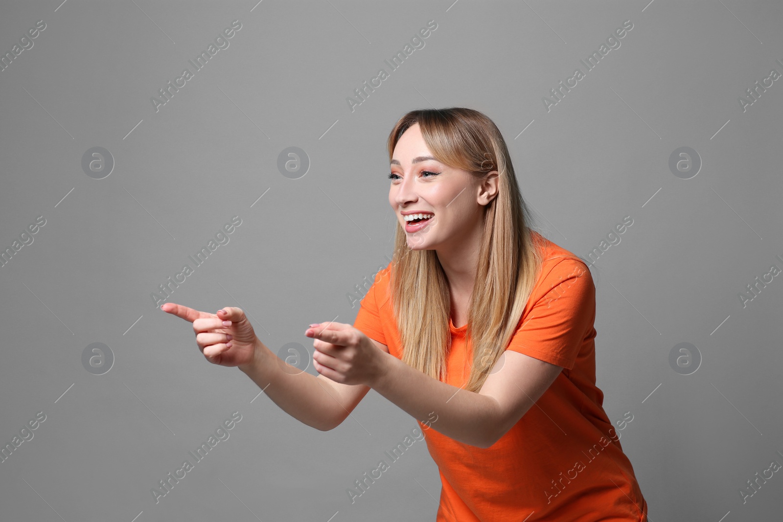 Photo of Beautiful young woman laughing on grey background. Funny joke