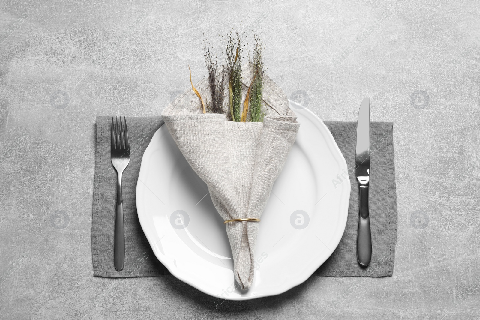 Photo of Plates with fabric napkin, decorative ring and cutlery on gray background, flat lay