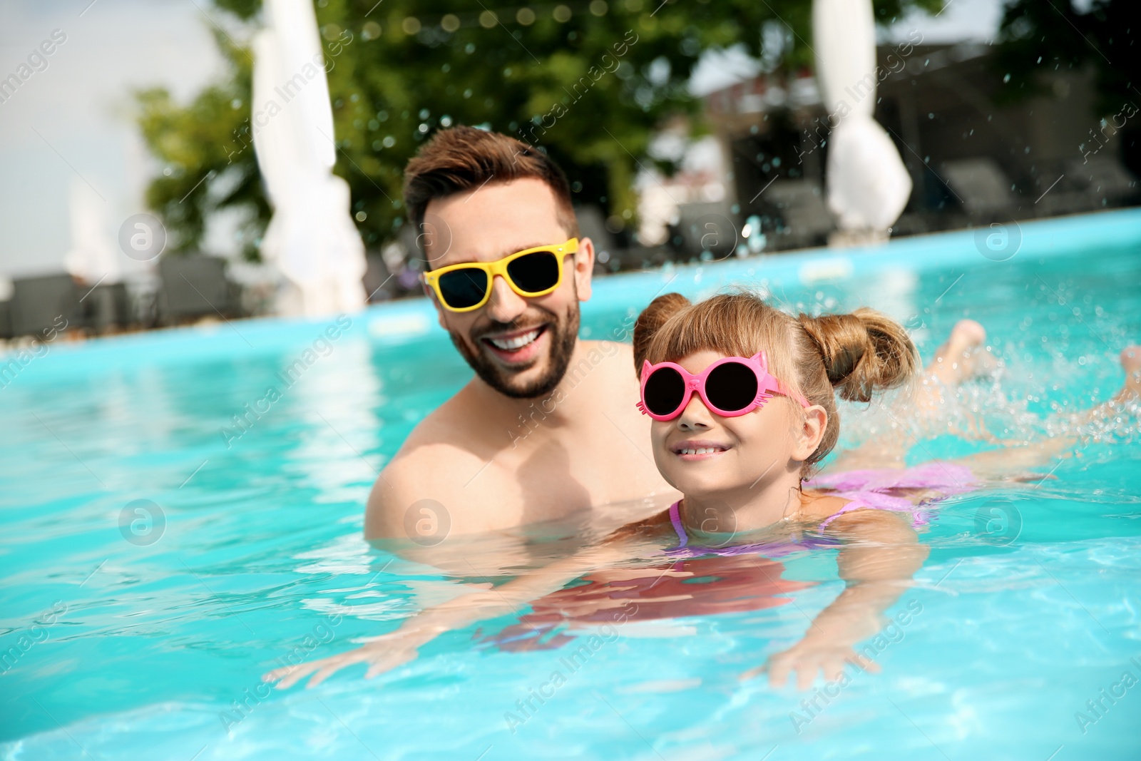 Photo of Father and daughter having fun in swimming pool. Family vacation