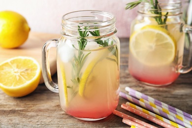 Photo of Refreshing lemon cocktail with rosemary in mason jars on table