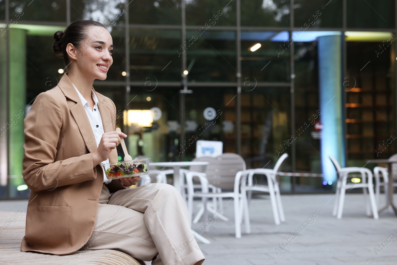 Photo of Happy young businesswoman eating lunch on bench outdoors