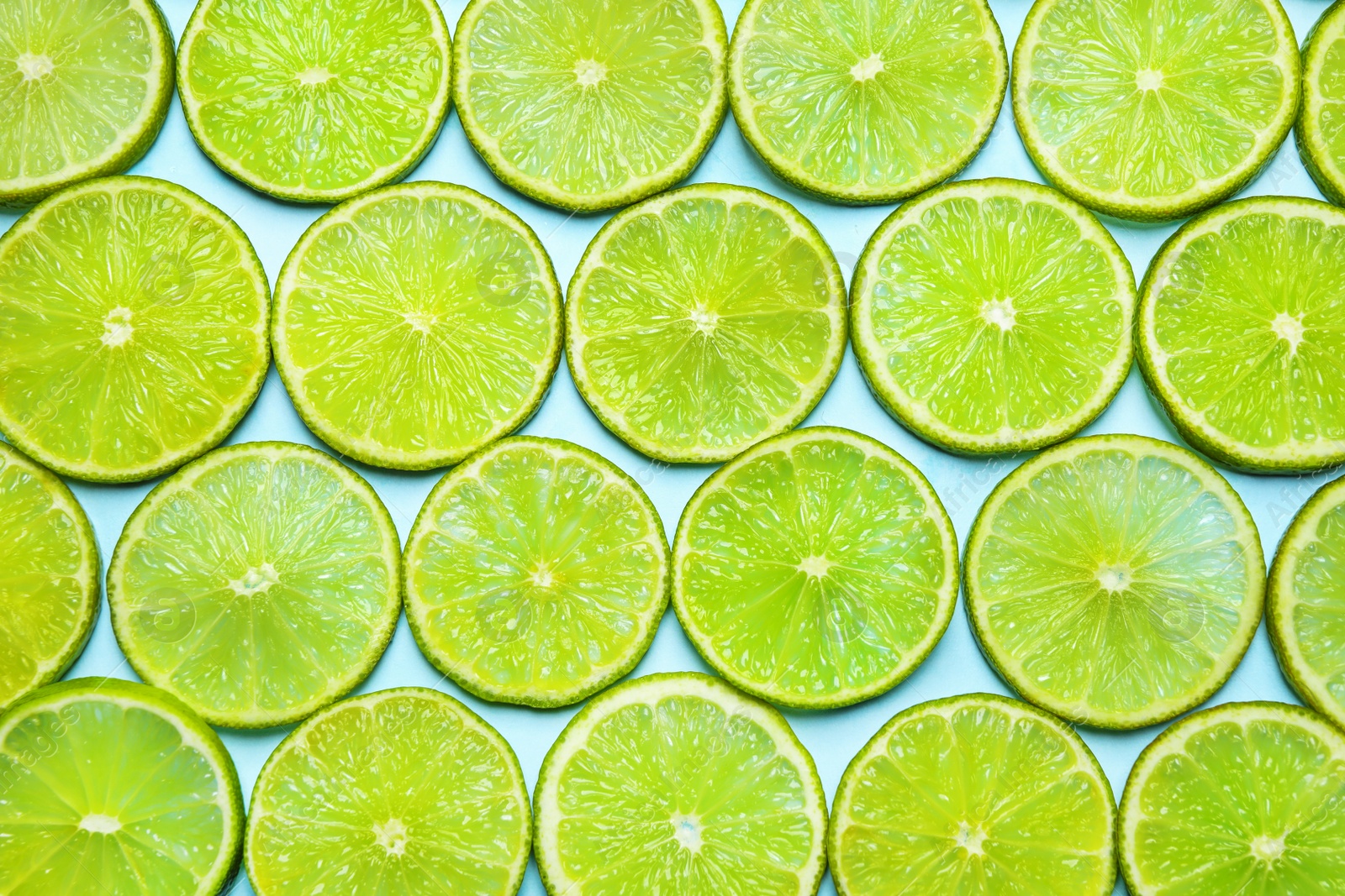 Photo of Juicy fresh lime slices on light blue background, flat lay