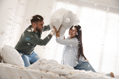 Photo of Happy young couple having fun pillow fight in bedroom