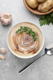 Photo of Delicious cream soup with soy sauce and parsley served on grey marble table, flat lay