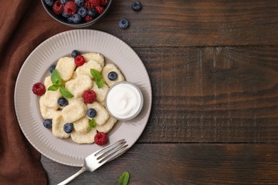 Photo of Plate of tasty lazy dumplings with berries, sour cream and mint leaves on wooden table, flat lay. Space for text