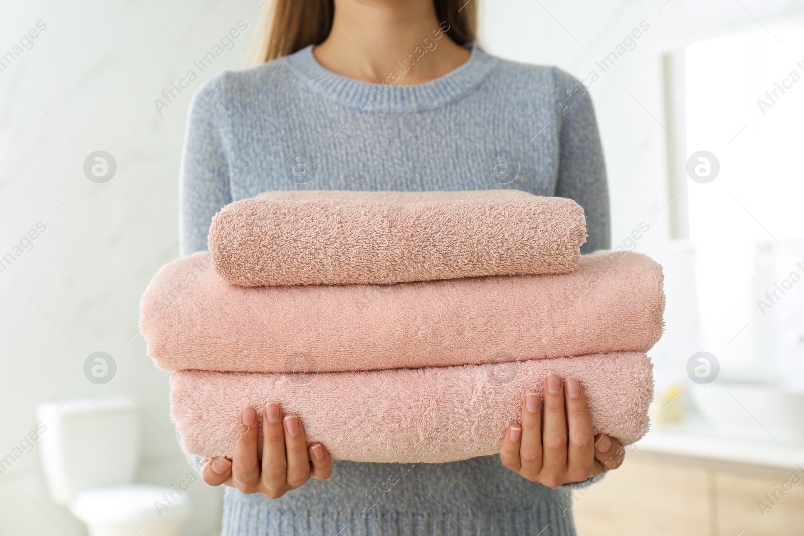 Photo of Woman holding fresh towels in bathroom, closeup