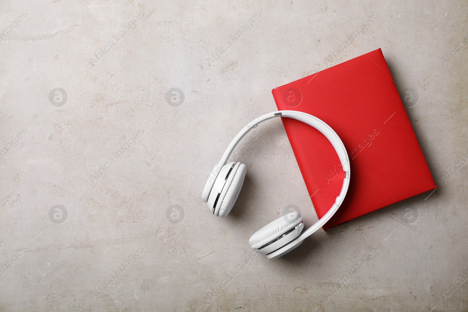 Photo of Modern headphones with hardcover book on grey background, top view. Space for text