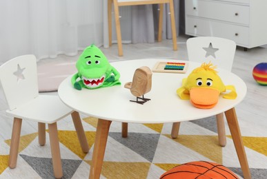 Different toys on white table and chairs in playroom. Kindergarten interior design