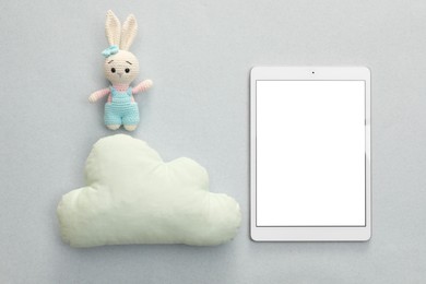 Modern tablet, toy cloud and bunny on light background, flat lay. Space for text
