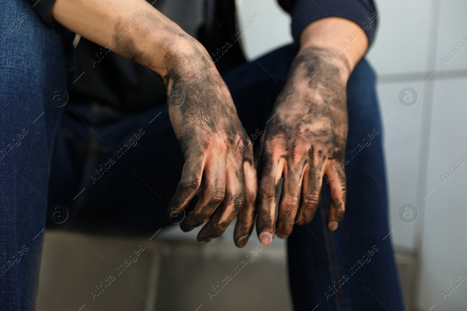 Photo of Dirty worker sitting on stairs, closeup of hands