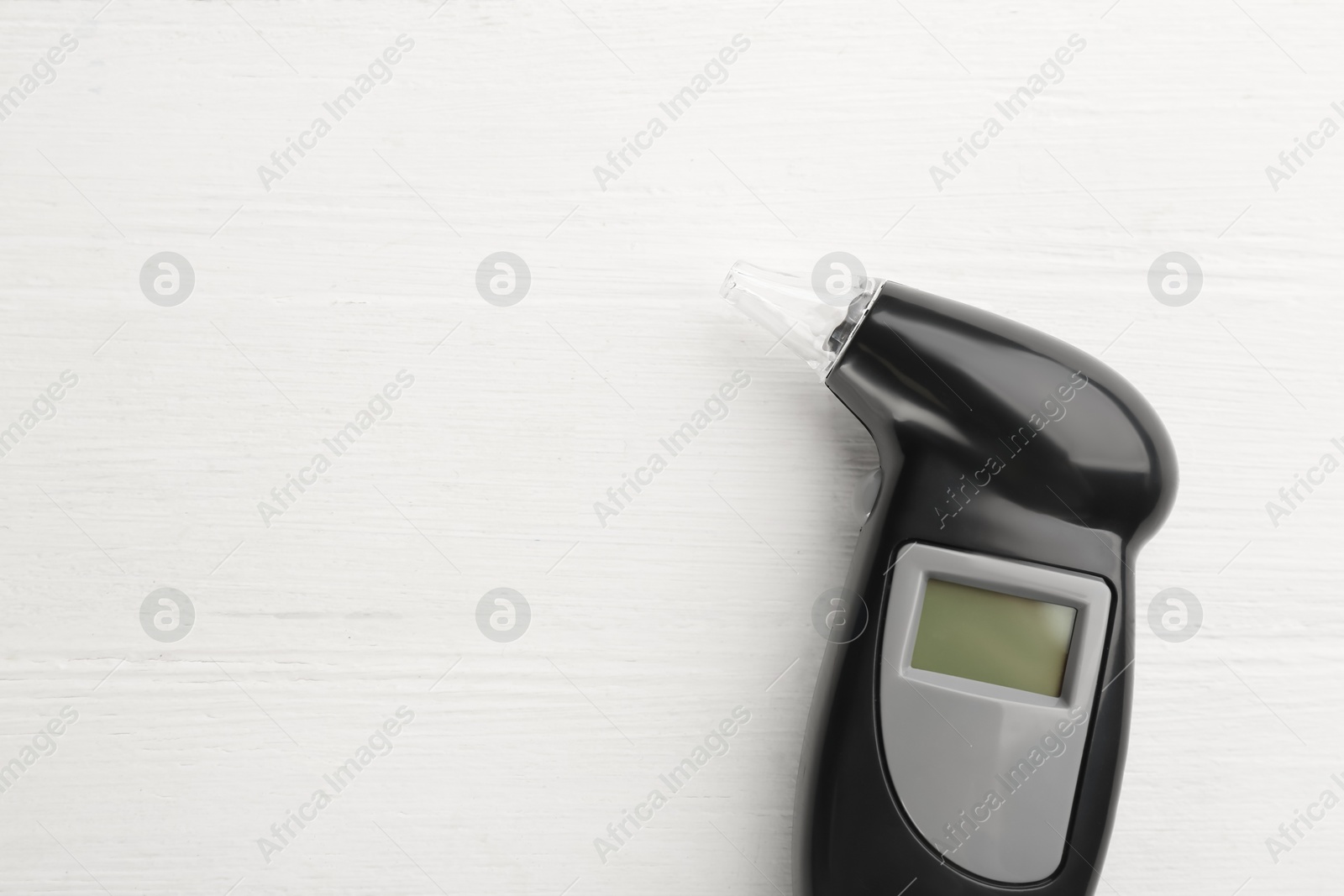 Photo of Modern breathalyzer on white wooden background, top view. Space for text