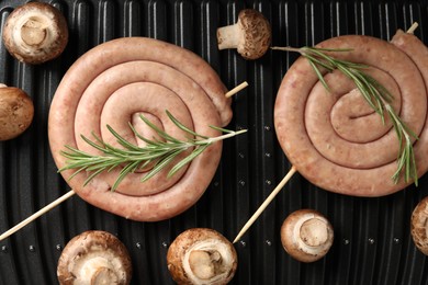 Photo of Homemade sausages, rosemary and mushrooms on electric grill, top view