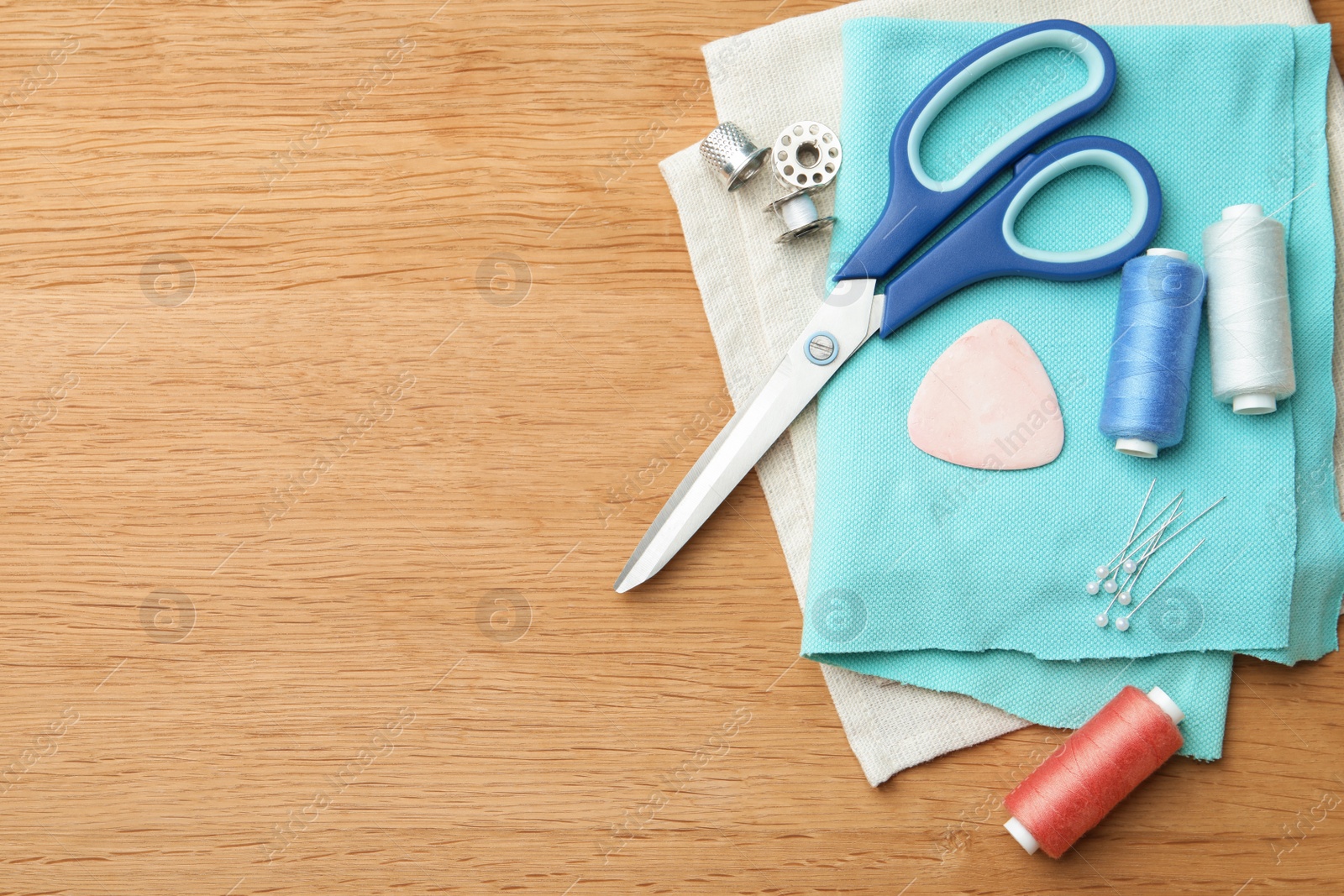 Photo of Flat lay composition with spools of threads and sewing tools on wooden table. Space for text