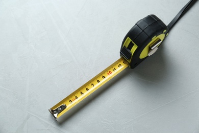 Tape measure on light grey background, above view. Construction tool