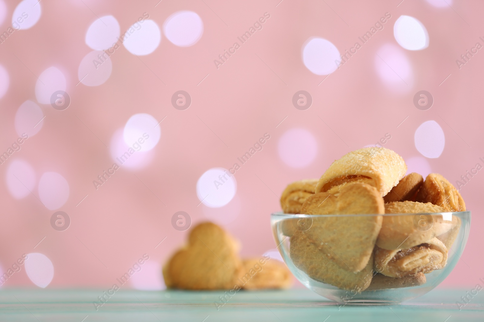 Photo of Delicious cookies in bowl on table against blurred background, closeup. Space for text