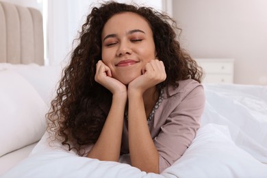 Photo of Happy African American woman lying on bed at home