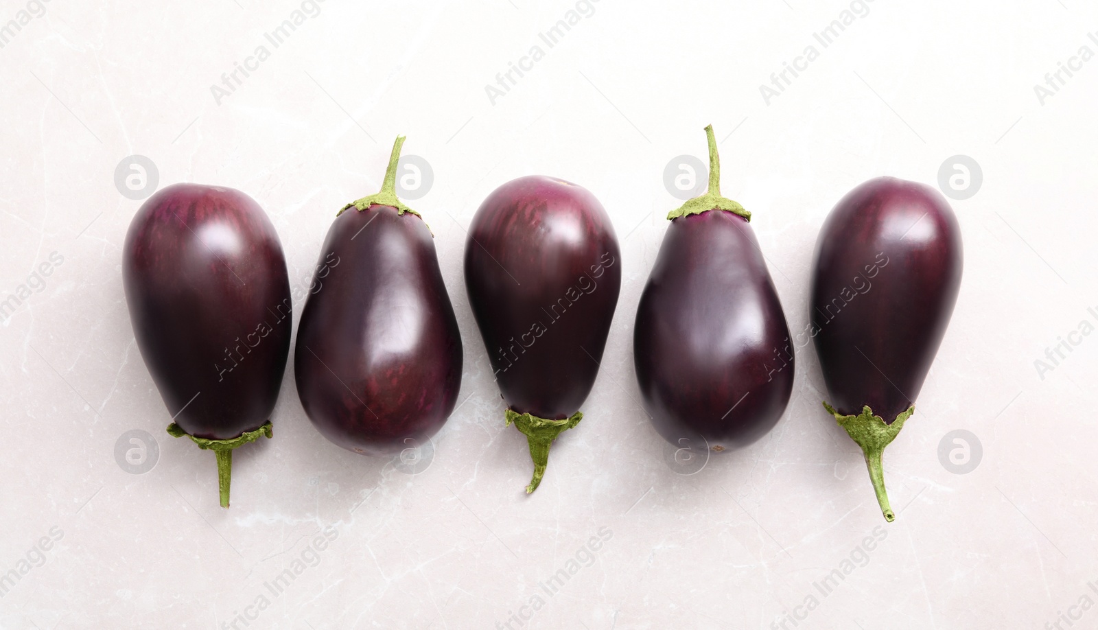 Photo of Raw ripe eggplants on light table, flat lay