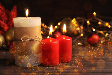 Image of Burning candles and Christmas decoration on wooden table, bokeh effect