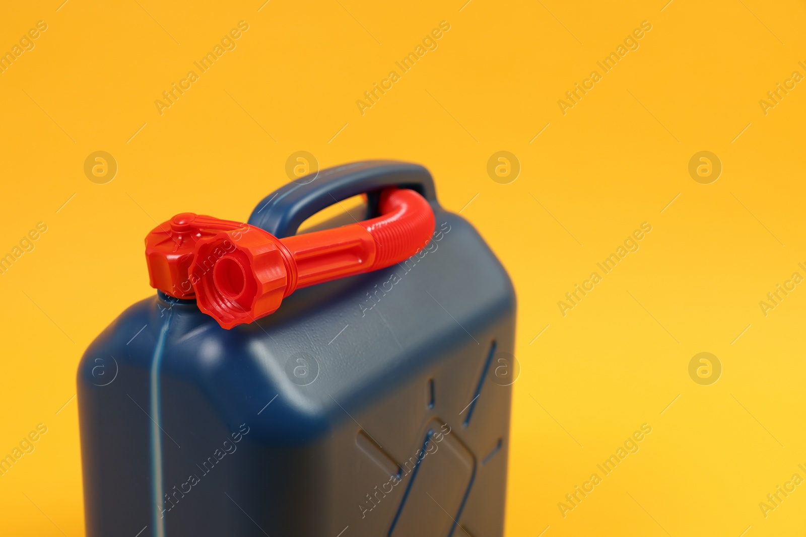 Photo of Blue plastic canister with tube on orange background, closeup. Space for text