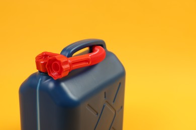 Photo of Blue plastic canister with tube on orange background, closeup. Space for text