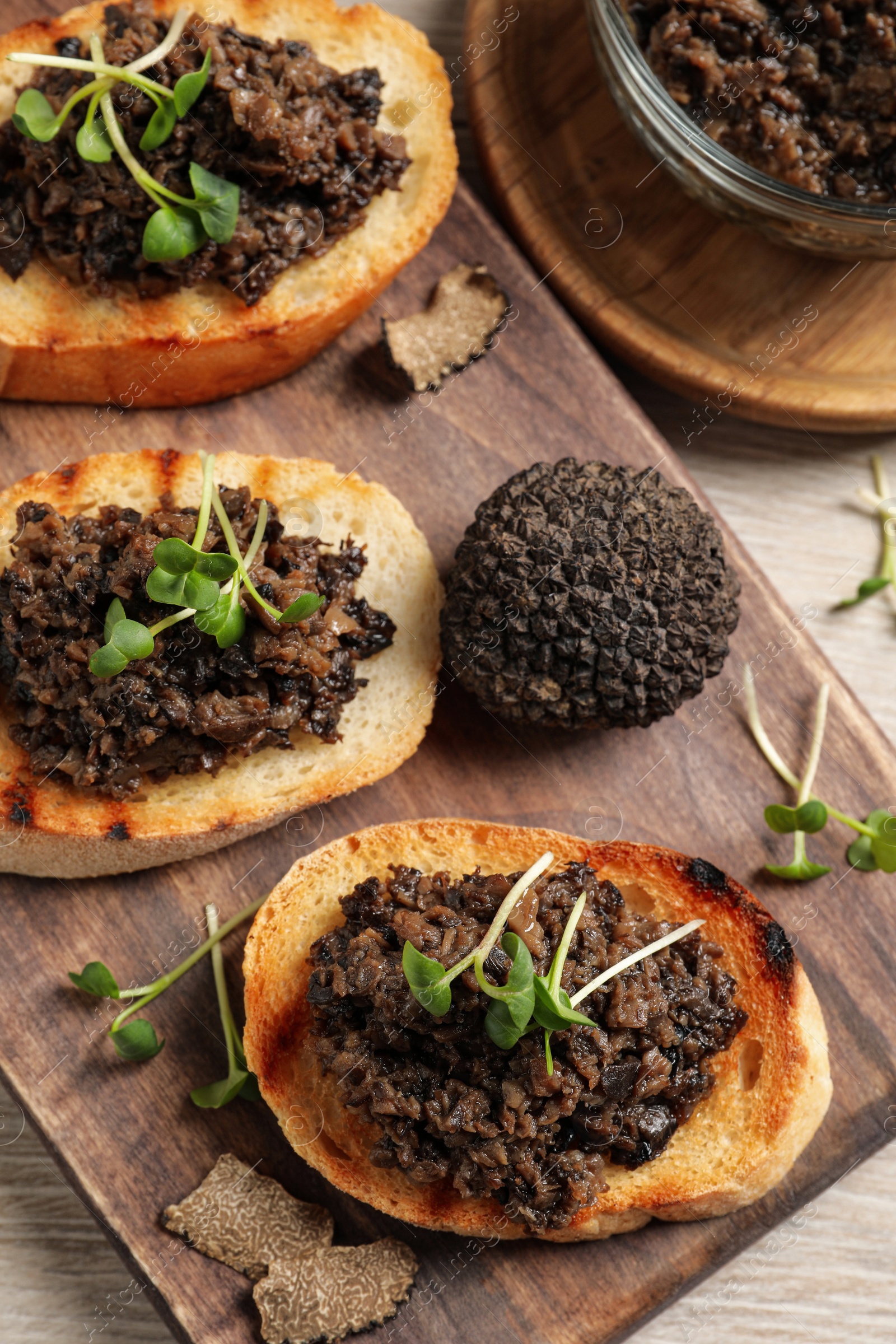 Photo of Delicious bruschettas with truffle sauce and microgreens on white wooden table, flat lay