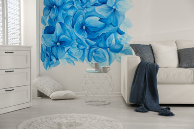 Stylish living room with blue flowers painted on wall. Floral pattern in interior design