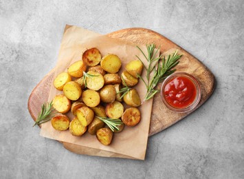 Photo of Tasty baked potato with aromatic rosemary and sauce served on grey textured table, flat lay