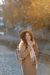 Portrait of beautiful African-American woman with stylish beige backpack on city street