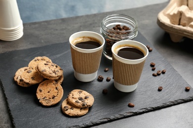 Composition with aromatic hot coffee in paper cups and cookies on table