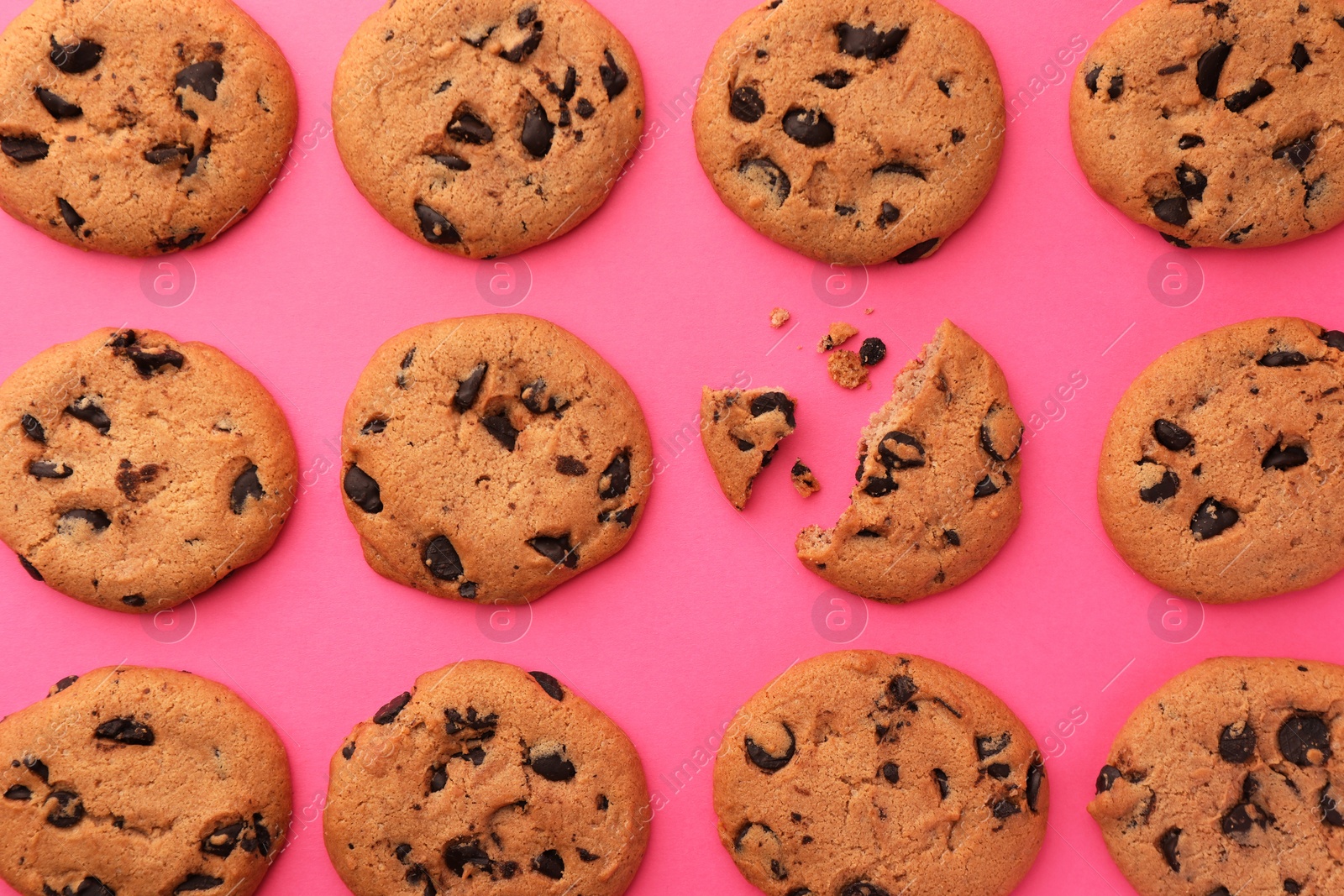 Photo of Many delicious chocolate chip cookies on pink background, flat lay