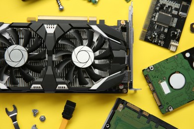 Graphics card and other computer hardware on yellow background, flat lay