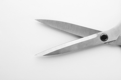 Photo of Pair of sharp sewing scissors on white background, closeup