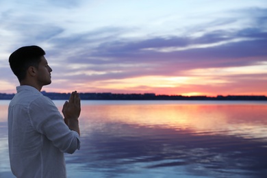 Man near river at sunset, space for text. Nature healing power