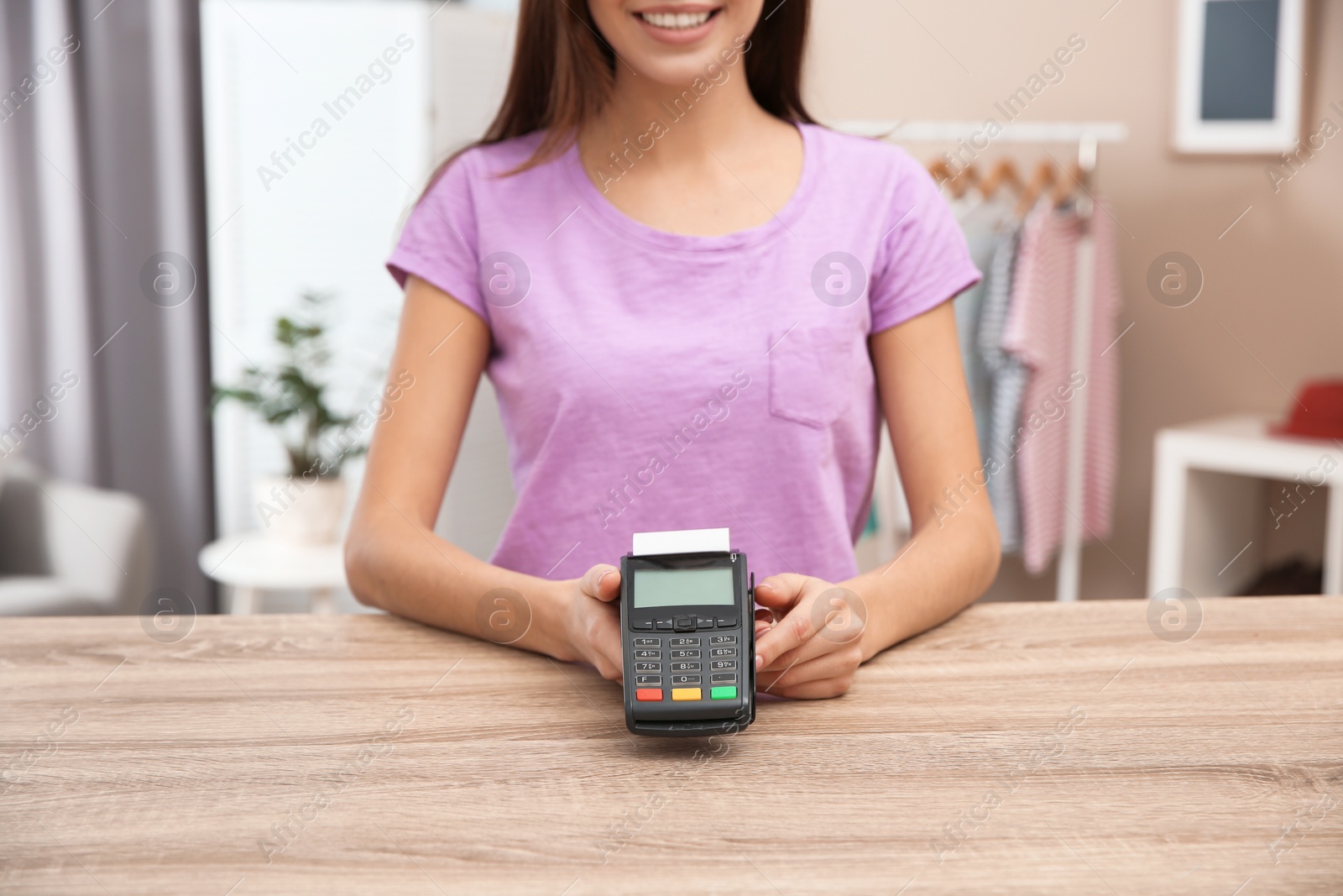 Photo of Female shop assistant with terminal for contactless payment at counter, closeup