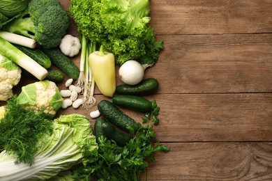 Different fresh ripe vegetables on wooden table, flat lay. Space for text