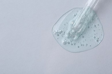 Photo of Pipette with cosmetic serum on white background, top view. Space for text