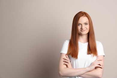 Photo of Candid portrait of happy young woman with charming smile and gorgeous red hair on beige background, space for text