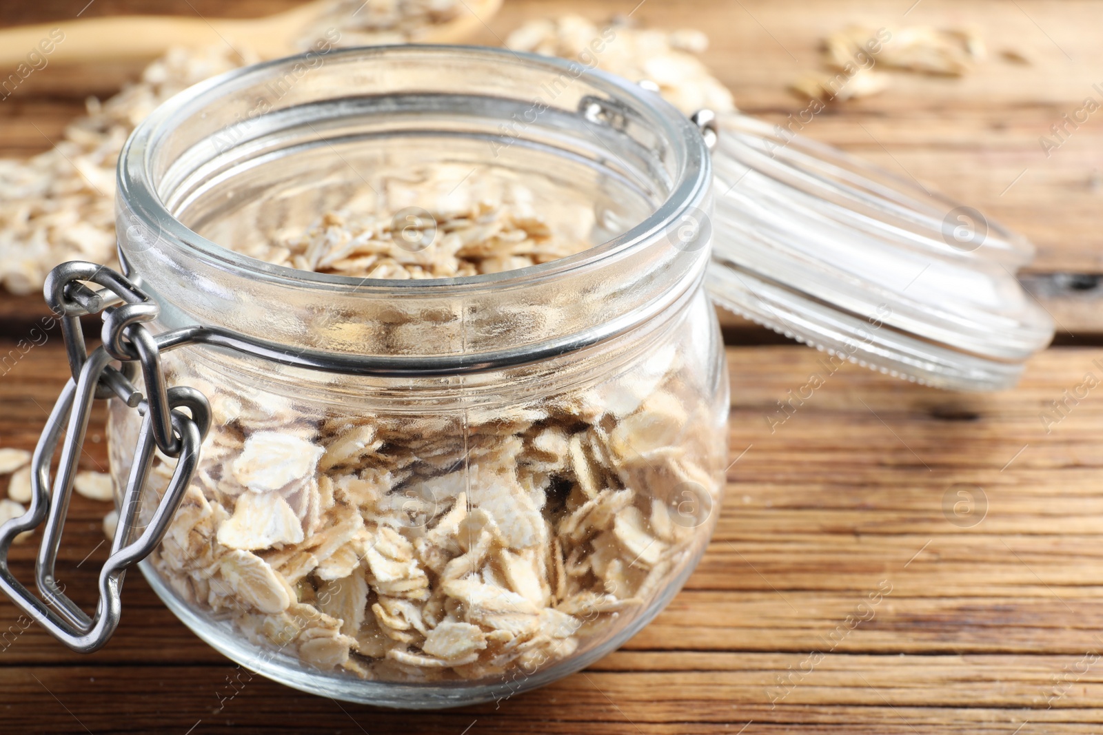 Photo of Glass jar with oatmeal on wooden table, closeup