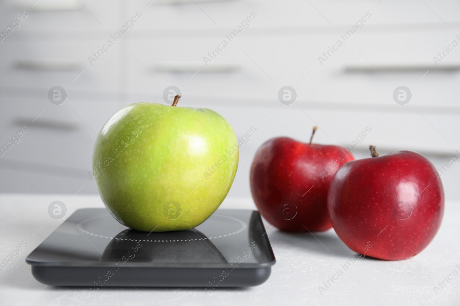 Photo of Ripe apples and modern digital scale on table