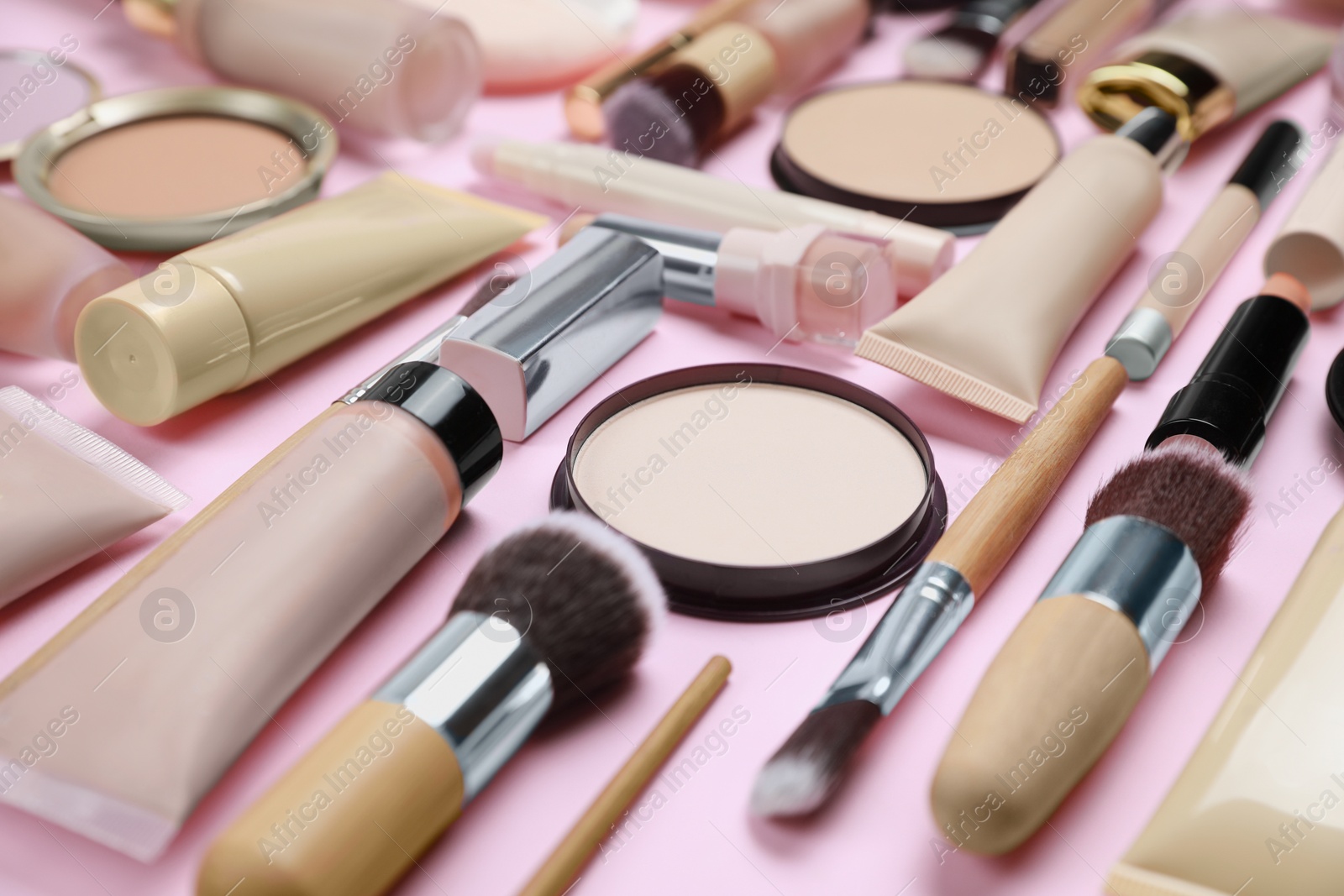 Photo of Face powders and other decorative cosmetic products on pink background