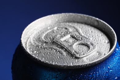 Photo of Aluminum can of beverage covered with water drops on blue background, closeup
