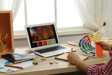 Photo of Female designer working at wooden table indoors, closeup