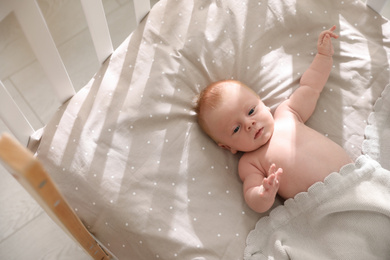 Photo of Cute little child lying in cot, above view. Healthy baby